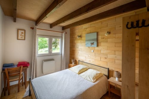 Chambre douillette avec poutres apparentes, lit queen-size et vue forêt au Domaine Des Escouanes