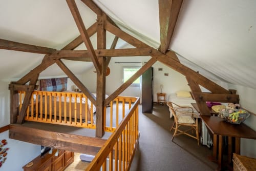 Chambre loft rustique avec poutres apparentes, deux lits bébé jaunes et vue sur jardin au gîte Domaine Des Escouanes