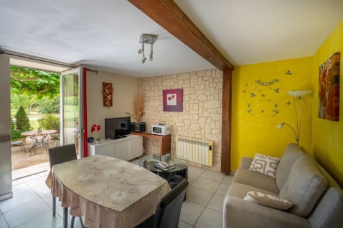 Chambre lumineuse avec mur jaune, mobilier beige, cheminée en pierre et vue sur le jardin au Domaine Des Escouanes
