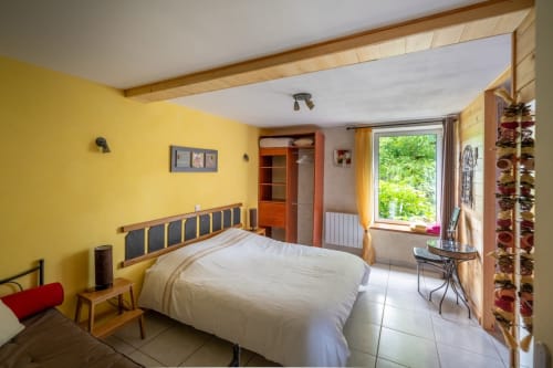 Chambre jaune lumineux avec vue sur le jardin au gîte Domaine Des Escouanes, literie blanche et équipements modernes