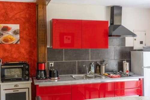 Cuisine moderne rouge et grise du gîte Côté Couleurs au Domaine Des Escouanes, Prudhomat avec évier en acier inoxydable