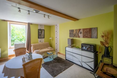 Séjour ensoleillé jaune vif avec vue sur le jardin au gîte Domaine Des Escouanes, avec coin salon, TV et table à manger