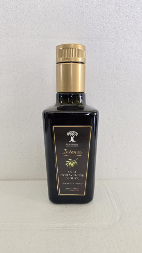 Bottiglia di olio extravergine di oliva Fogliantica con tappo dorato ed etichetta nera su sfondo bianco