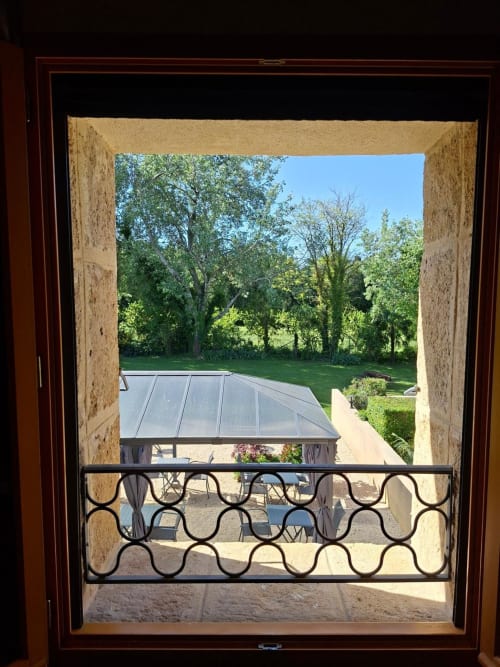 Vue depuis le balcon de la Chambre Cigale au Mas des Vergers à Salon-de-Provence, surplombant la cour, les jardins et les arbres