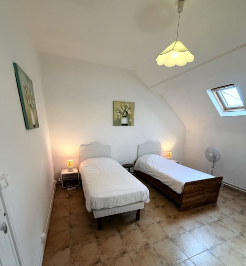 Twin bedroom with white bedding at Les gites de Lereau, Vallières-les-Grandes, featuring yellow pendant lamp and skylight.