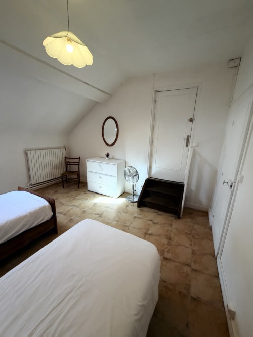Bright attic bedroom at Les gites de Lereau with two beds, white dresser, and modern pendant light