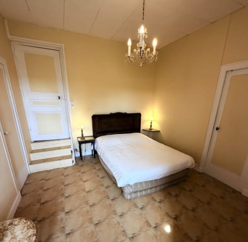 Elegant bedroom at Les gites de Lereau with double bed, chandelier, and cream walls in Vallières-les-Grandes