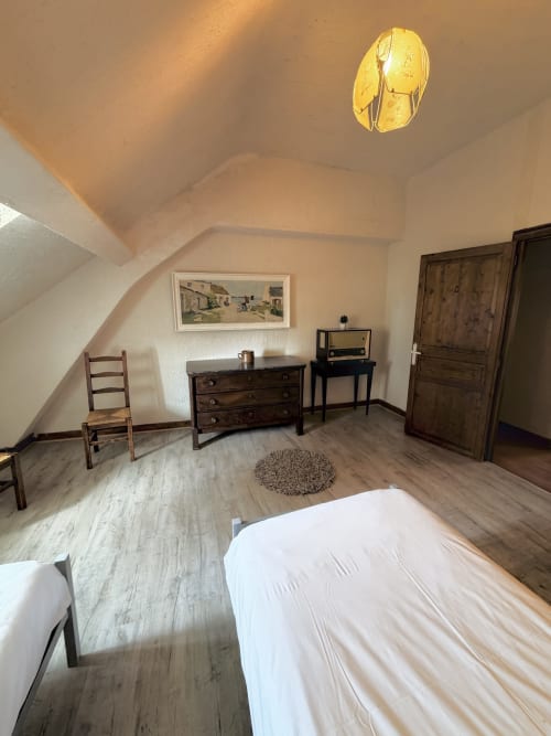 Attic bedroom at Les gites de Lereau with sloped ceilings, wooden furniture, and white bedding in Vallières-les-Grandes