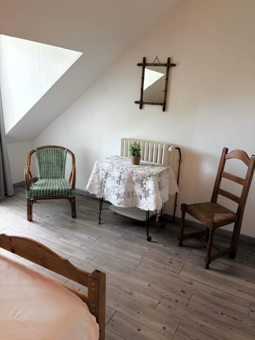 Cozy attic bedroom at Les gites de Lereau with vintage furniture, lace tablecloth, and natural skylight