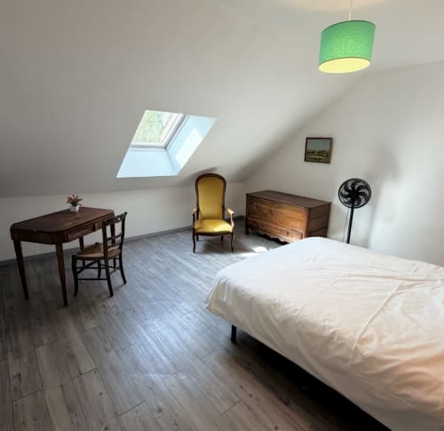 Bright attic bedroom at Les gites de Lereau with bed, wooden desk, armchair, and skylight in Vallières-les-Grandes