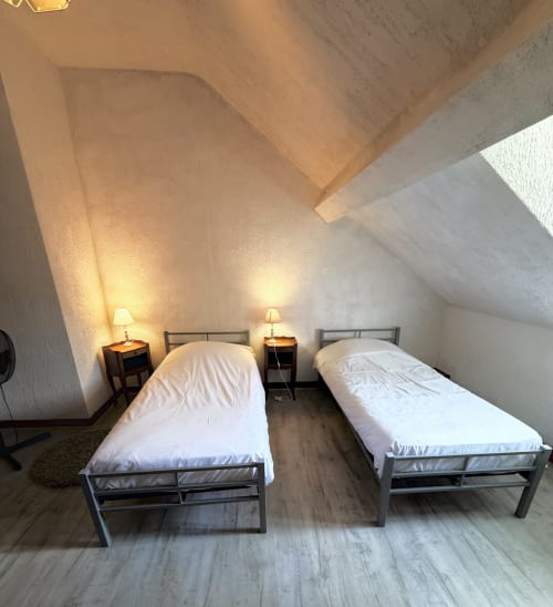 Twin bedroom in attic room at Les gites de Lereau, Vallières-les-Grandes, with white bedding and warm lighting