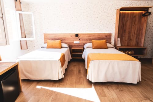 Habitación doble en Hostal Restaurante Angel de Huelma con camas de madera, ropa blanca y decoración acogedora