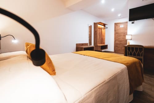 Habitación moderna en el Hostal Restaurante Angel de Huelma con camas individuales, muebles de madera e iluminación cálida