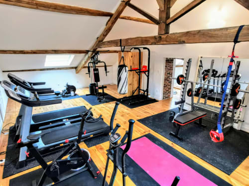 Salle de fitness moderne à Vindihouses à Epinac avec tapis roulants, vélos d'exercice, haltères et tapis de yoga