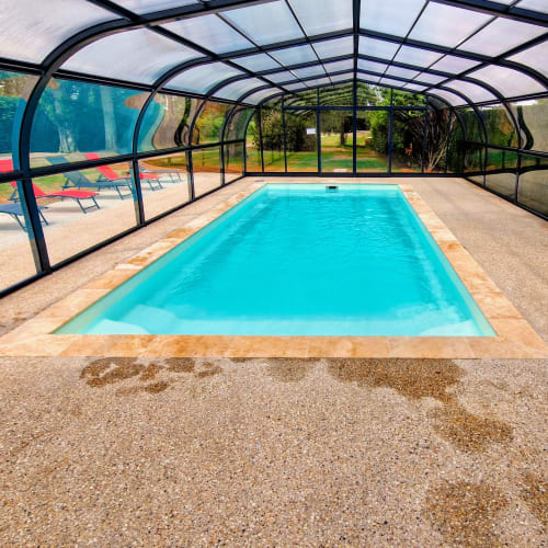 Covered heated pool at La Villa 1848 cottage in Épinac with lounge chairs and garden views