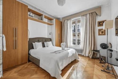 Elegant bedroom at Résidence Aurmat boutique hotel in Boulogne with wooden wardrobes, parquet floors, and Parisian windows
