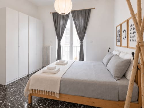 Camera da letto moderna presso Easystay Bari Apartment con letto in legno, biancheria grigia, guardaroba bianco e balcone con tende grigie
