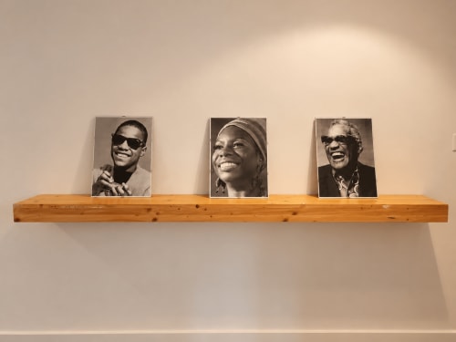 Tre fotografie di ritratti in bianco e nero esposte su uno scaffale in legno nella camera dell'appartamento Easystay Bari