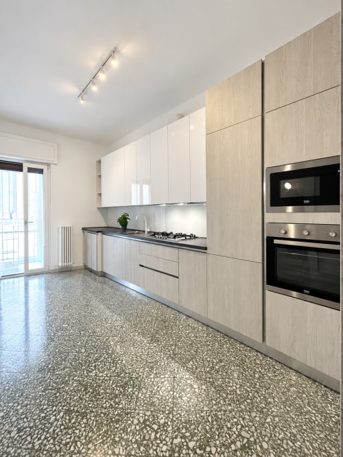 Cucina moderna dell'appartamento Easystay Bari con armadi in legno chiaro, piano di lavoro nero e elettrodomestici in acciaio inossidabile