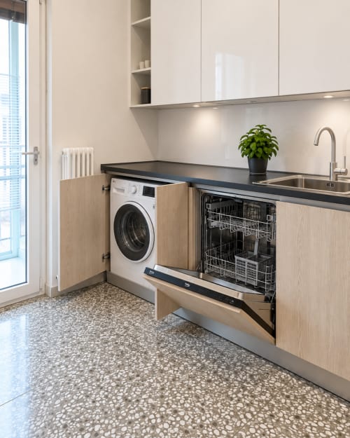 Moderna lavanderia presso Easystay Bari con lavatrice integrata, lavastoviglie, lavello e piano nero