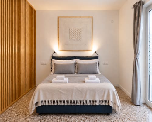 Camera moderna a Easystay Bari con letto queen, parete in legno, quadri incorniciati e illuminazione contemporanea a Bari, Italia