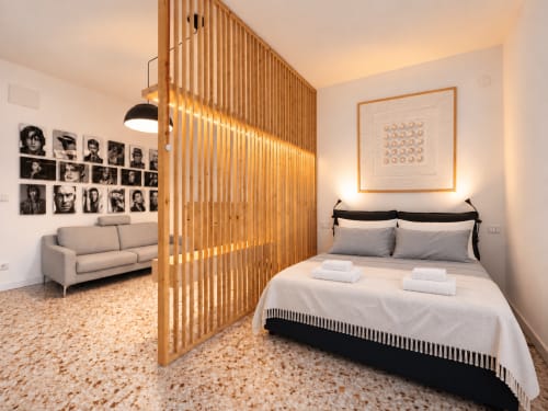Moderno studio-camera presso Easystay Bari con divisorio in legno, letto, zona living e arte murale in bianco e nero
