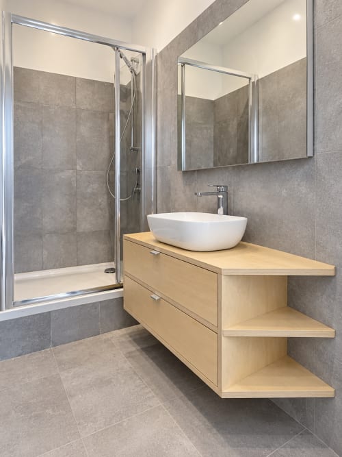 Bagno moderno presso Easystay Bari con piastrelle grigie, lavabo bianco, mobile in legno, specchio e doccia