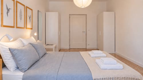 Camera moderna presso Easystay Bari con biancheria blu, cornici in legno, porte bianche e artwork con uccelli
