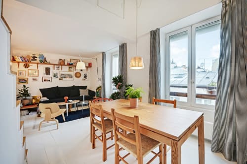 Lumineux loft ouvert à Montmartre avec table en bois, canapé noir et baies vitrées donnant sur Paris