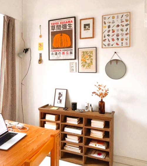 Espace de travail cosy à Montmartre avec bureau orange, étagères en bois, mur galerie et objets décoratifs à Paris