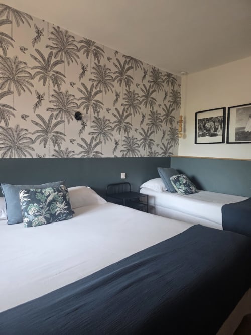 Chambre triple de l'Hôtel Les Lauriers, Saint-Tropez, avec lits jumeaux, mur d'accent papier peint tropical et jardin