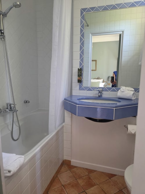 Salle de bain moderne de l'Hôtel Les Lauriers à Saint-Tropez avec vasque bleue, miroir, douche et carrelage