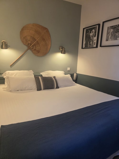 Chambre d'hôtel moderne à l'Hôtel Les Lauriers à Saint-Tropez avec literie blanche, décoration en éventail tressé et tableaux encadrés