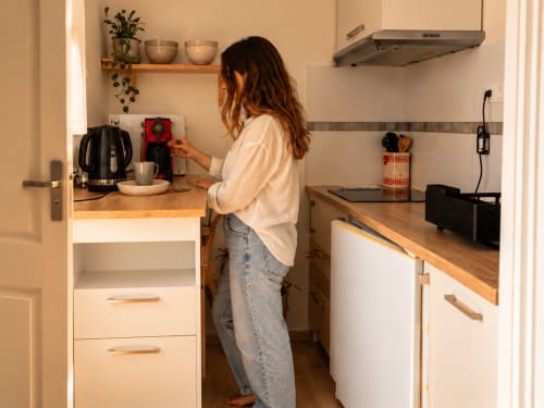 Femme dans la kitchenette du gîte de Chaparon à Lathuile, préparant un café avec une machine à espresso rouge