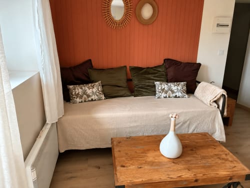 Chambre douillette au gîte de Chaparon avec lit beige, mur d'accent rouge et coussins décoratifs à Lathuile