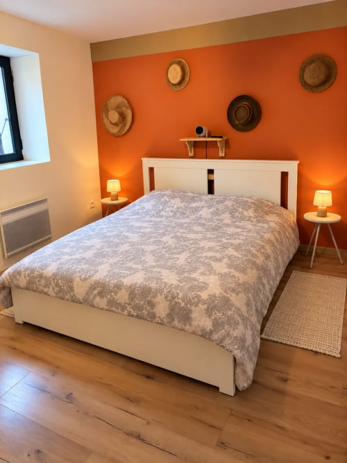 Chambre Bohème au gîte de Chaparon à Lathuile : murs orange vif, lit blanc et décoration de chapeaux tressés
