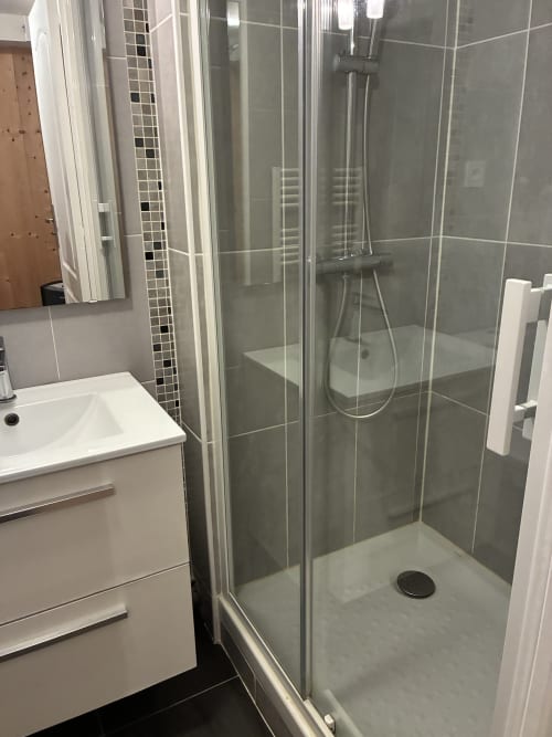 Salle de bain moderne avec douche à l'italienne, vasque blanche et murs en carrelage gris au gîte de Chaparon à Lathuile