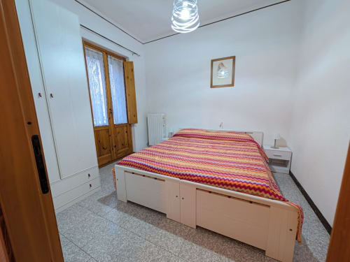 Chambre spacieuse de l'appartement Gio avec lit double, rangements, armoire blanche et vue sur les montagnes à Aymavilles