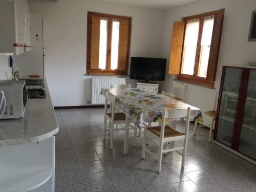 Zone cuisine-salle à manger lumineuse de l'appartement QUADRIFOGLIO à Gio Appartamenti, Aymavilles, avec nappe fleurie et chaises blanches