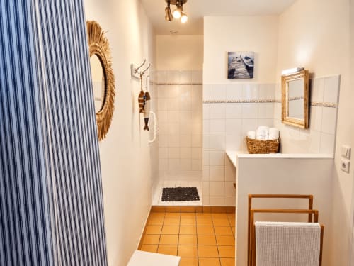Salle de bain privative de la chambre d’hôtes Avel à Ty Coz Breizh, à Guidel en Bretagne Sud, avec douche à l’italienne, miroirs en rotin et décoration marine.