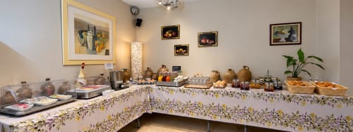 Hotel Les Oliviers breakfast buffet in Fayence with pastries, jams, and beverages on floral-patterned counter