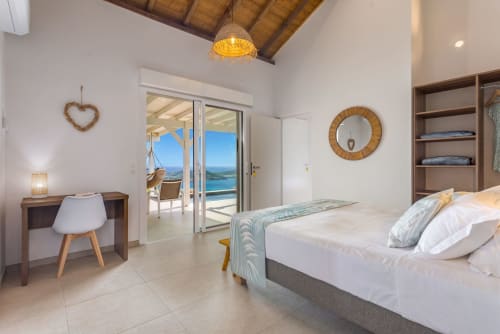 Chambre lumineuse à la villa Terrasses du Morne Gommier avec vue mer, lit moderne, bureau en bois et accès terrasse au Marin,