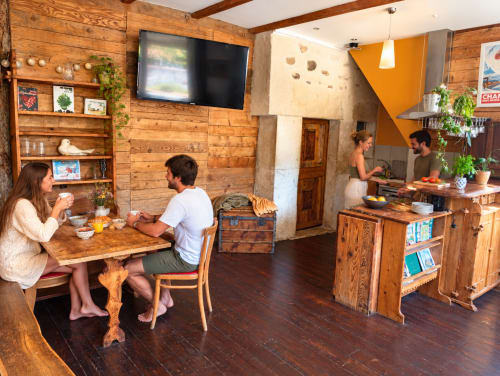 Salon commun chaleureux du gîte de Chaparon à Lathuile avec clients dînant, mobilier en bois, TV et vue sur les montagnes