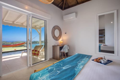 Villa lumineuse aux Antilles avec vue sur mer, literie à motifs bleus et accès à la terrasse