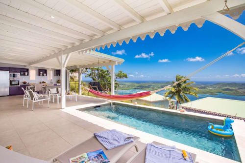 Terrasse de villa de luxe avec piscine à débordement surplombant Le Marin, Martinique, hamac et vue océan