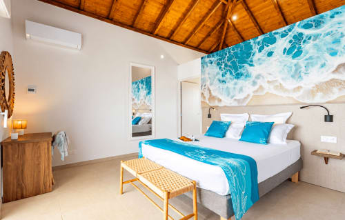 Chambre de villa face mer avec œuvre océanique, parure bleue, plafond bois et vue sur la mer aux Terrasses du Morne Gommier