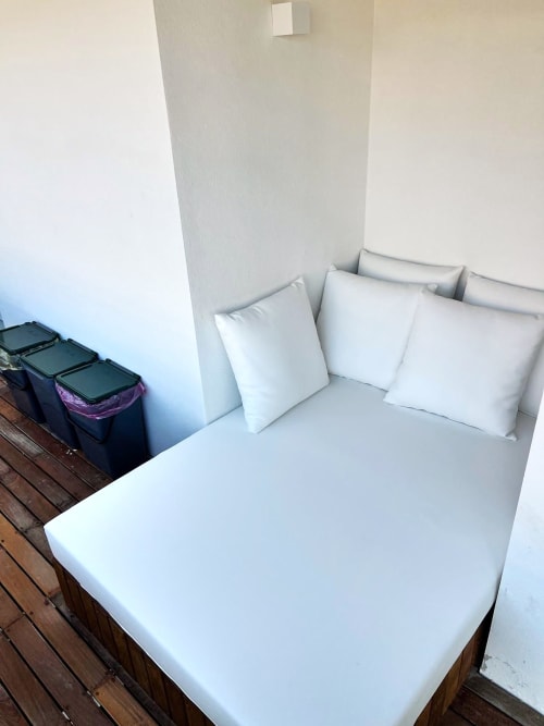 Biancheria e cuscini bianchi sul letto della camera da letto dell'appartamento a La Sciumara Resort Palau, con cestini neri e pavimento in legno