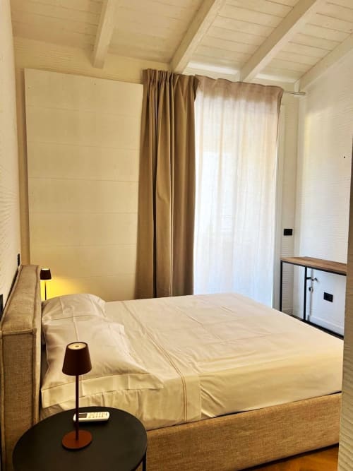 Camera da letto moderna e luminosa al La Sciumara Resort Palau con biancheria color crema, arredamento in legno e vista sul giardino