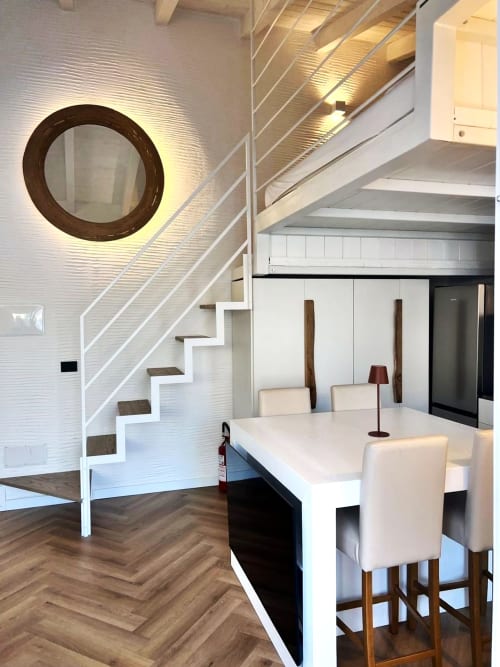 Moderno appartamento in stile loft a La Sciumara Resort Palau con scala a spirale bianca, pavimento in legno scuro e cucina a vista con zona pranzo