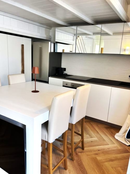 Cucina-sala da pranzo moderna a La Sciumara Resort Palau con bar bianco, elettrodomestici in acciaio inox e pavimenti in legno